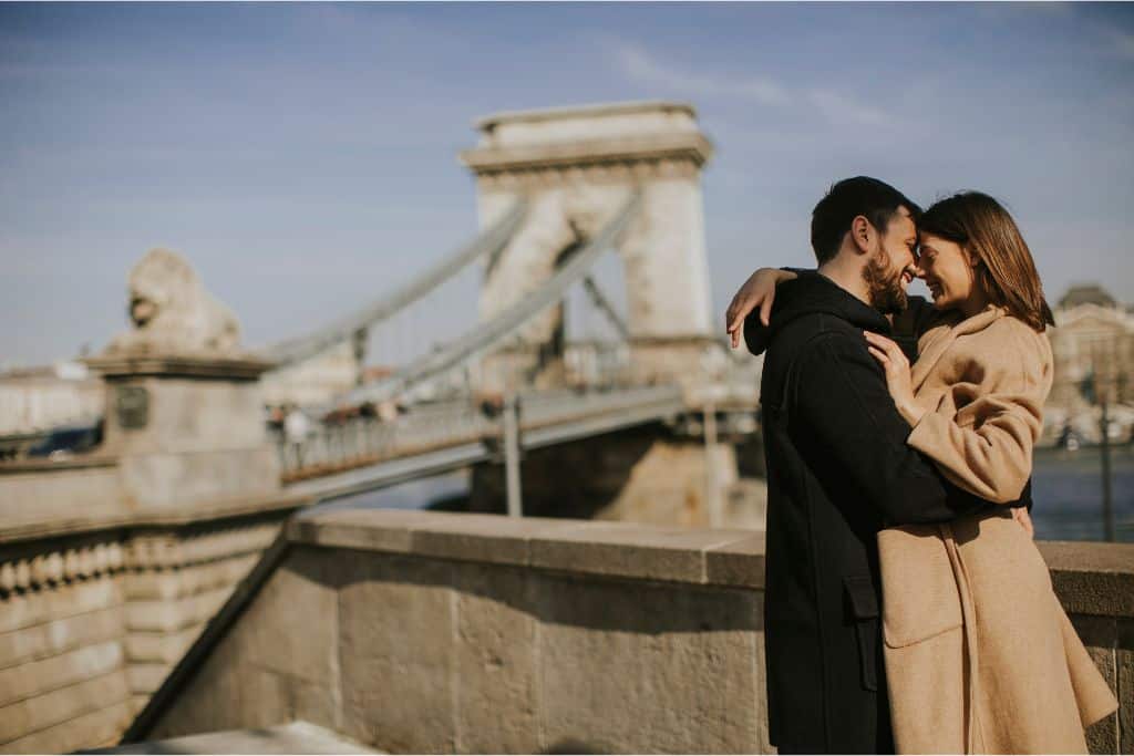 A couple embraces near the Széchenyi Chain Bridge in Budapest, Hungary