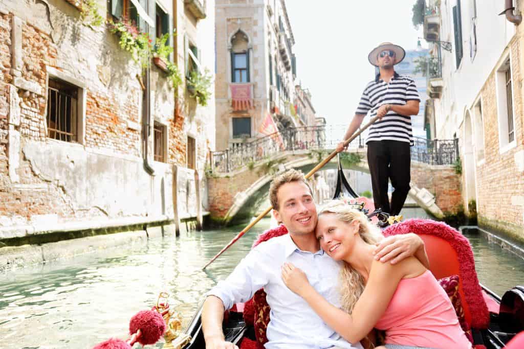 A couple enjoys a gondola ride on a canal in Venice, Italy, one of the most romantic cities in Europe