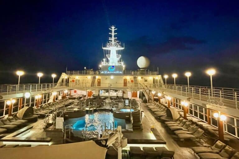 The deck of an Azamara ship at night with lots of white lights.