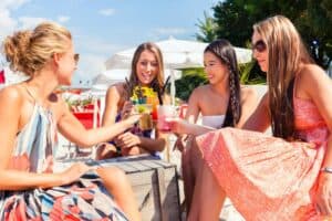 women on a girls' trip drinking cocktails on the beach in the Caribbean or Mexico