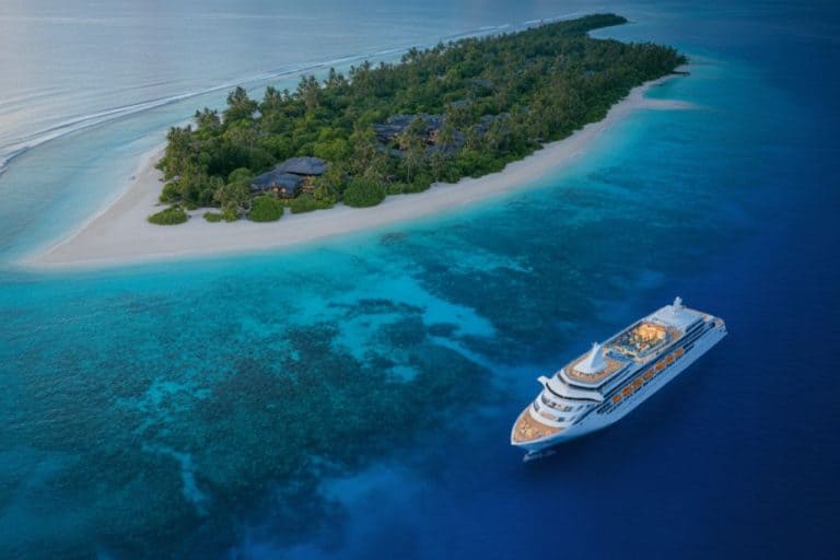 an aerial view of a cruise ship in blue waters near a Pacific island