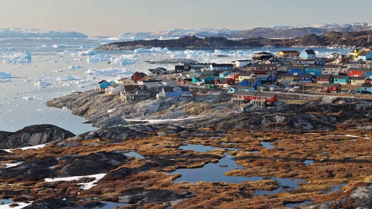 Colorful coastal town and icebergs along the shore in Greenland