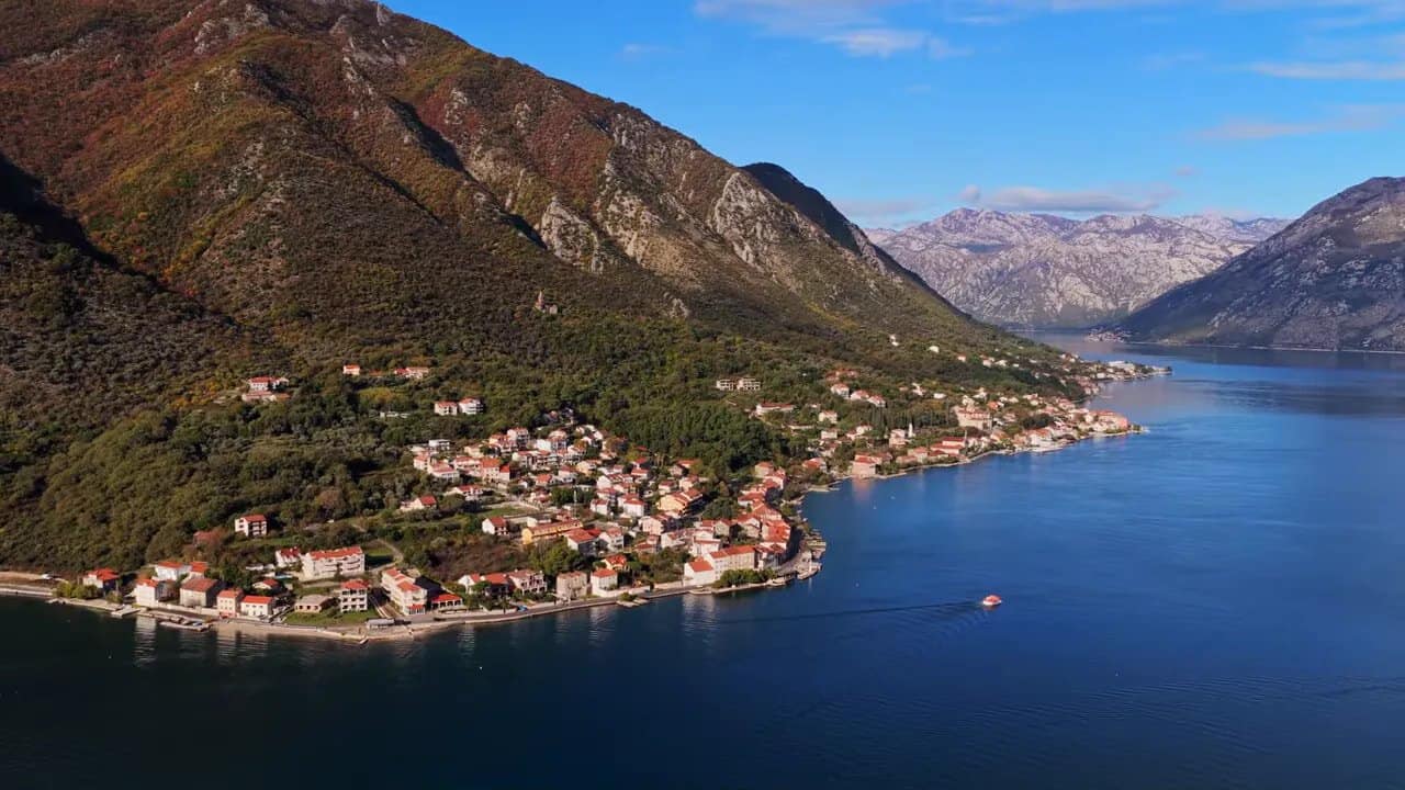 Aerial view of Kotor Bay with coastal town buildings and mountains in Montenegro