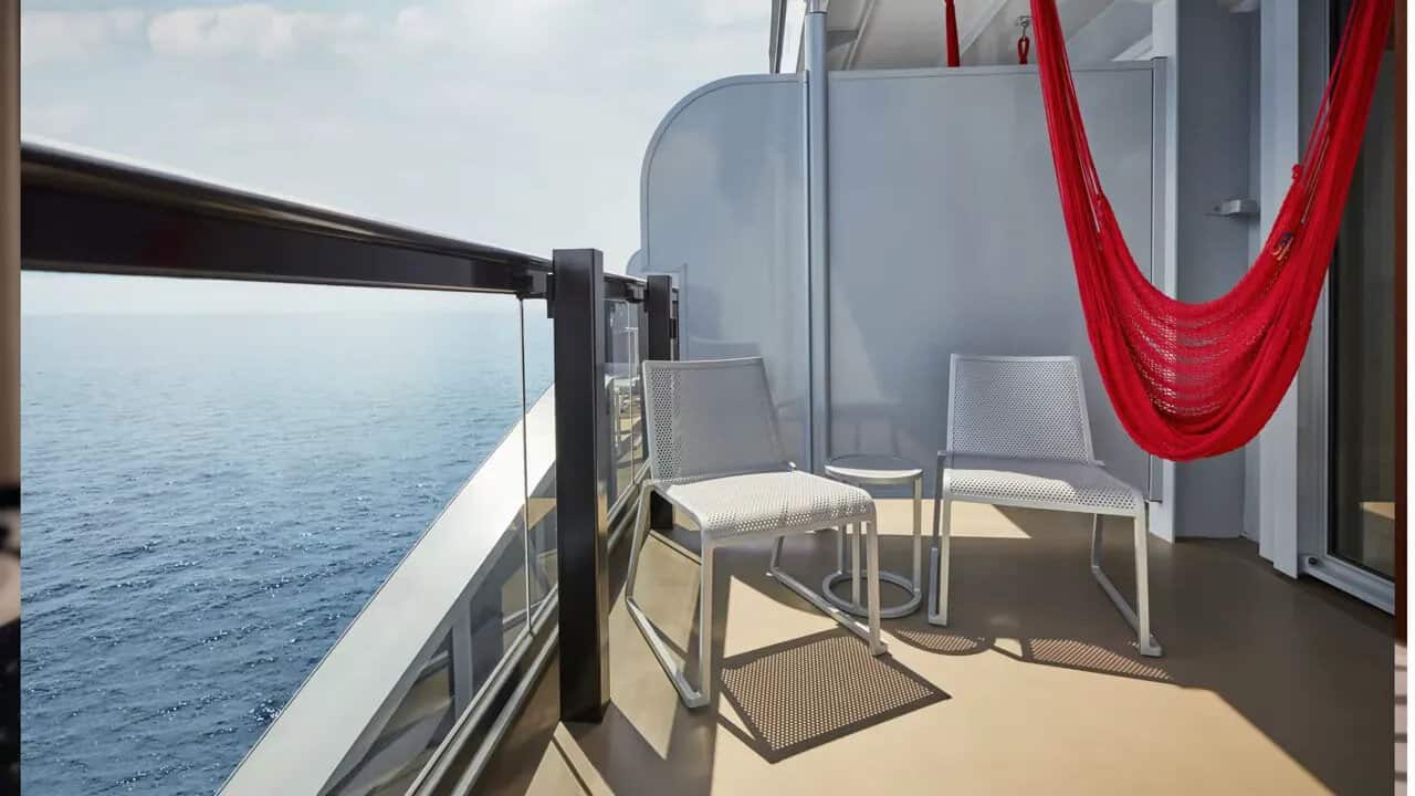 Balcony with red hammock, chair, small table, and ocean view